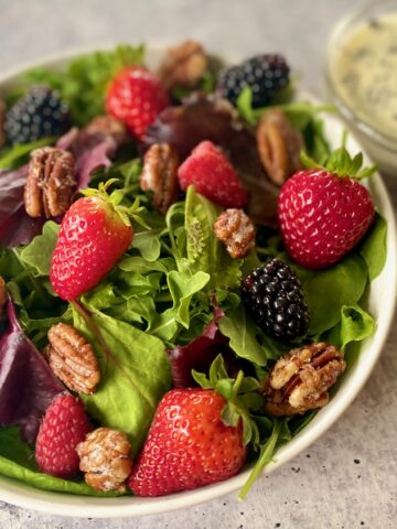 bowl of berry salad with bowl of dressing