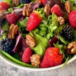 a bowl of strawberries, raspberries, blackberries and mixed greens