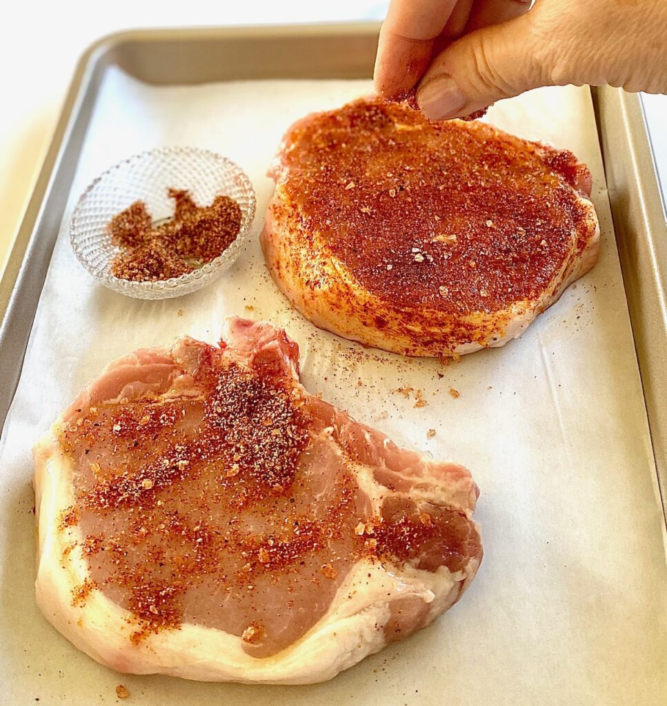 2 pork chops getting seasoned