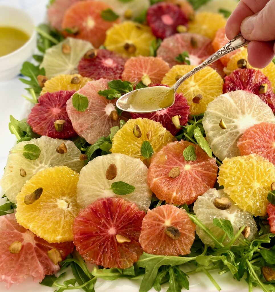 spooning dressing on sliced orange